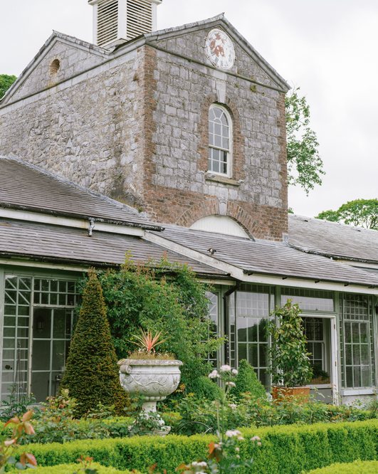 Stone clock tower above the conservatory and flower beds