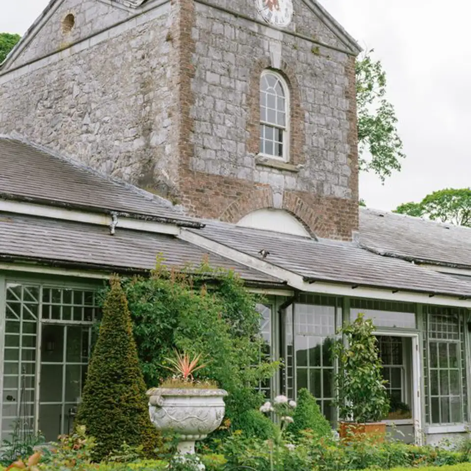 Stone clock tower above the conservatory and flower beds
